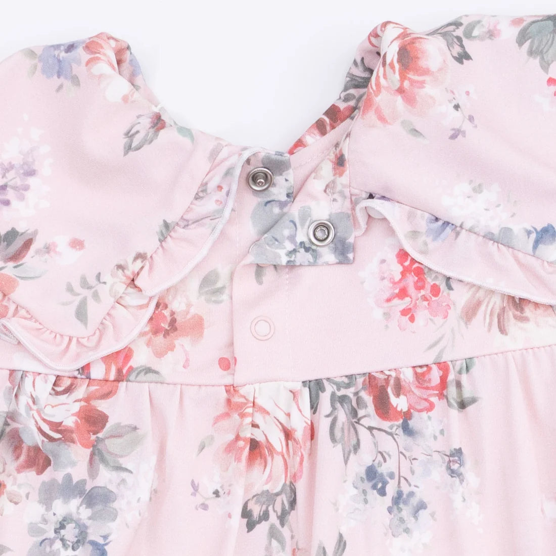 Floral patterned shirt with ruffled collar on a light pink background