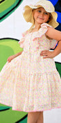 Young girl in a floral dress and sun hat posing in front of a colorful abstract background