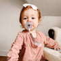 Baby with pacifier and linen clip attached to clothing