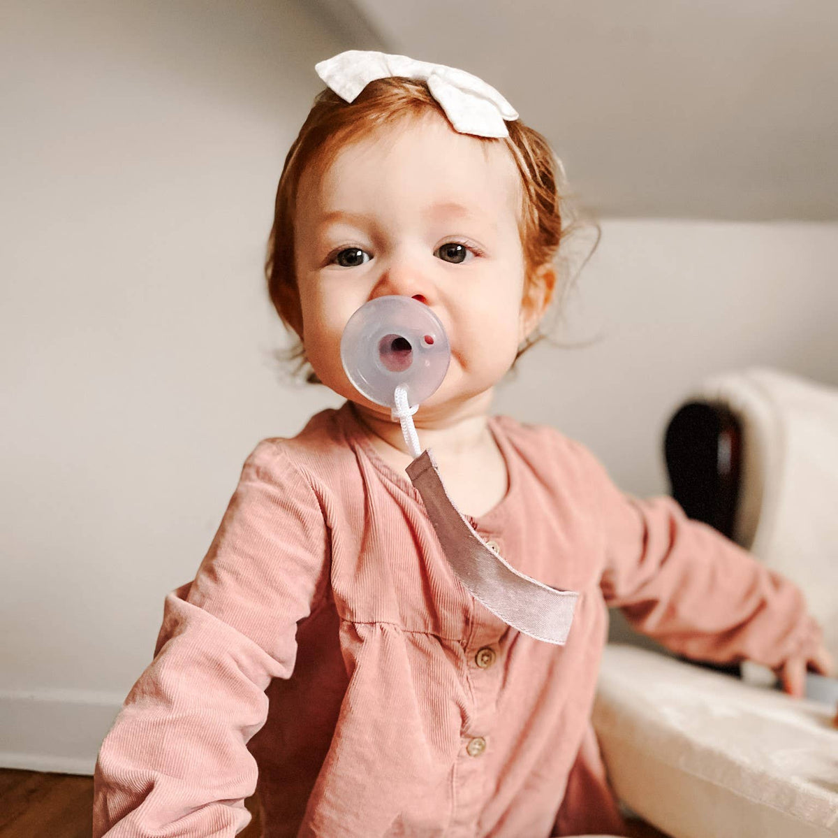 Baby with pacifier and linen clip attached to clothing