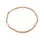 Bracelet with pink beads on a gold chain against a white background