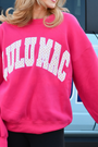 Hot pink sweatshirt with white polka-dot graphic, long sleeves and crew neck