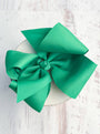 Green bow on a white plate with a light pink textured background