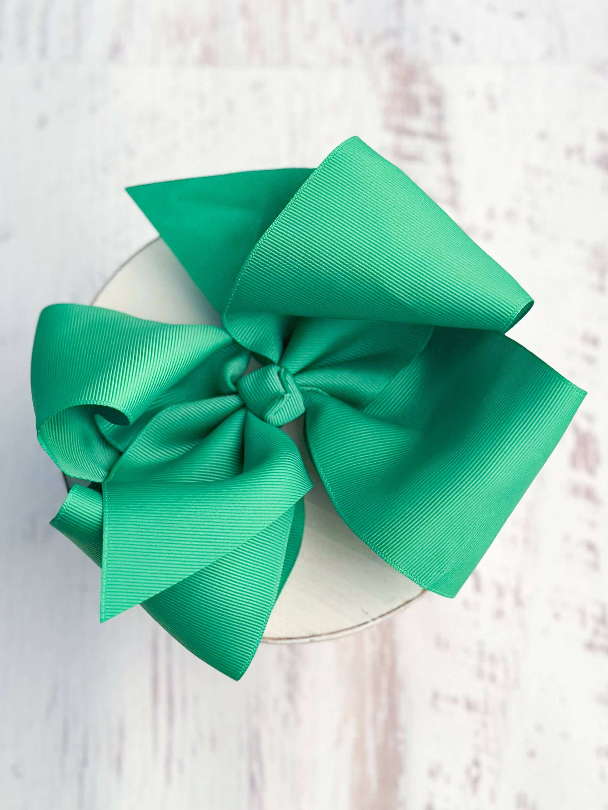 Green bow on a white plate with a light pink textured background