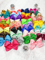 Assorted colorful hair bows on a light wooden surface with disco balls.