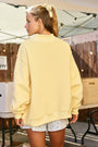 Person wearing a yellow sweatshirt and floral shorts in an outdoor setting
