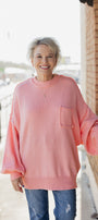 Person wearing a pink sweater with a pocket on a balcony