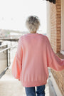 Person wearing a pink sweater standing on a balcony