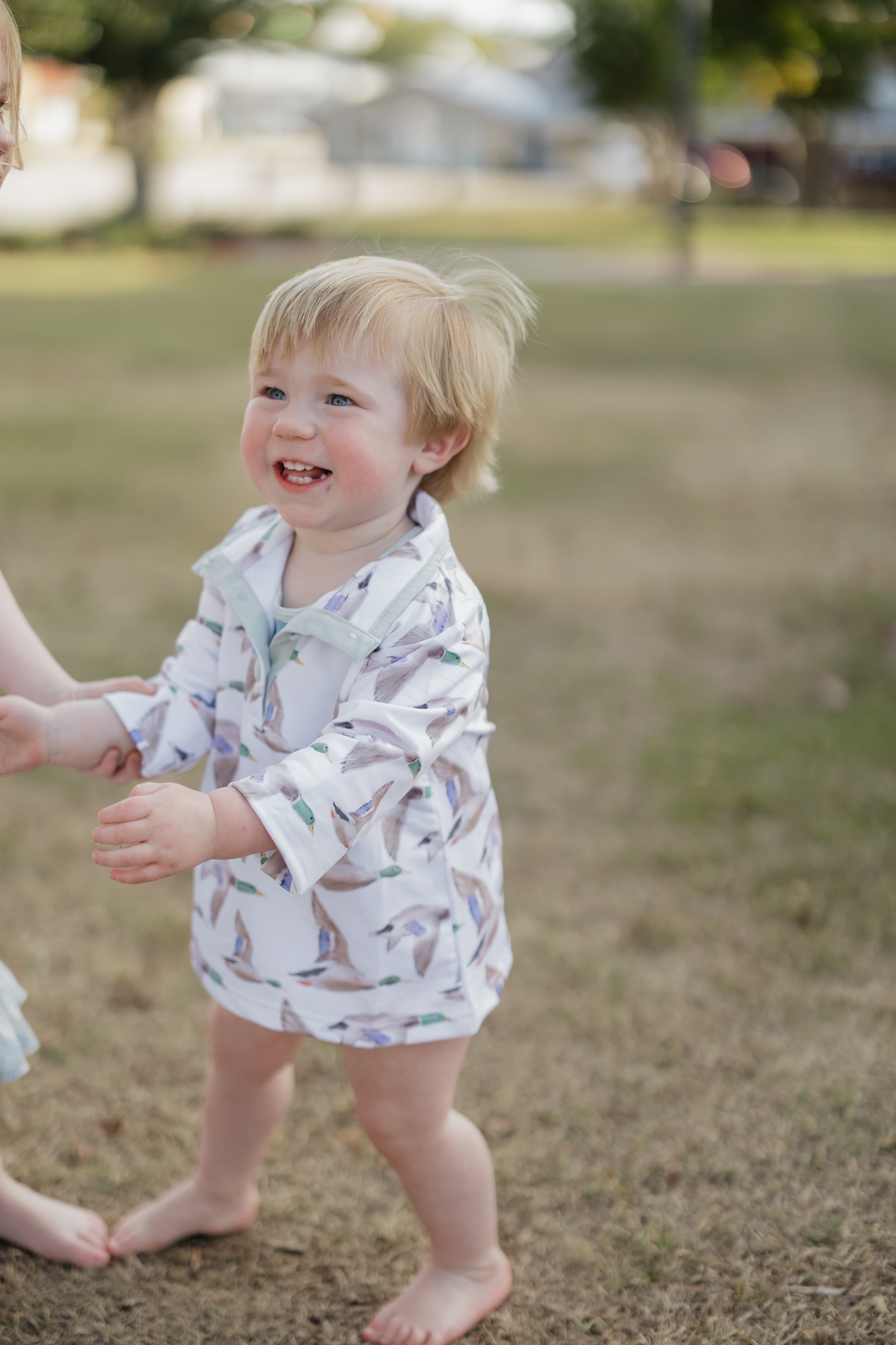 Child in a patterned outfit standing on grass