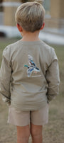 Child wearing a long-sleeve shirt with a graphic design on the back, standing outdoors.