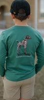 Person wearing a green long-sleeve shirt with a dog illustration and text, standing outdoors.