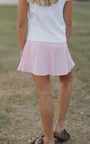Person wearing a white top and pink skirt standing on grass