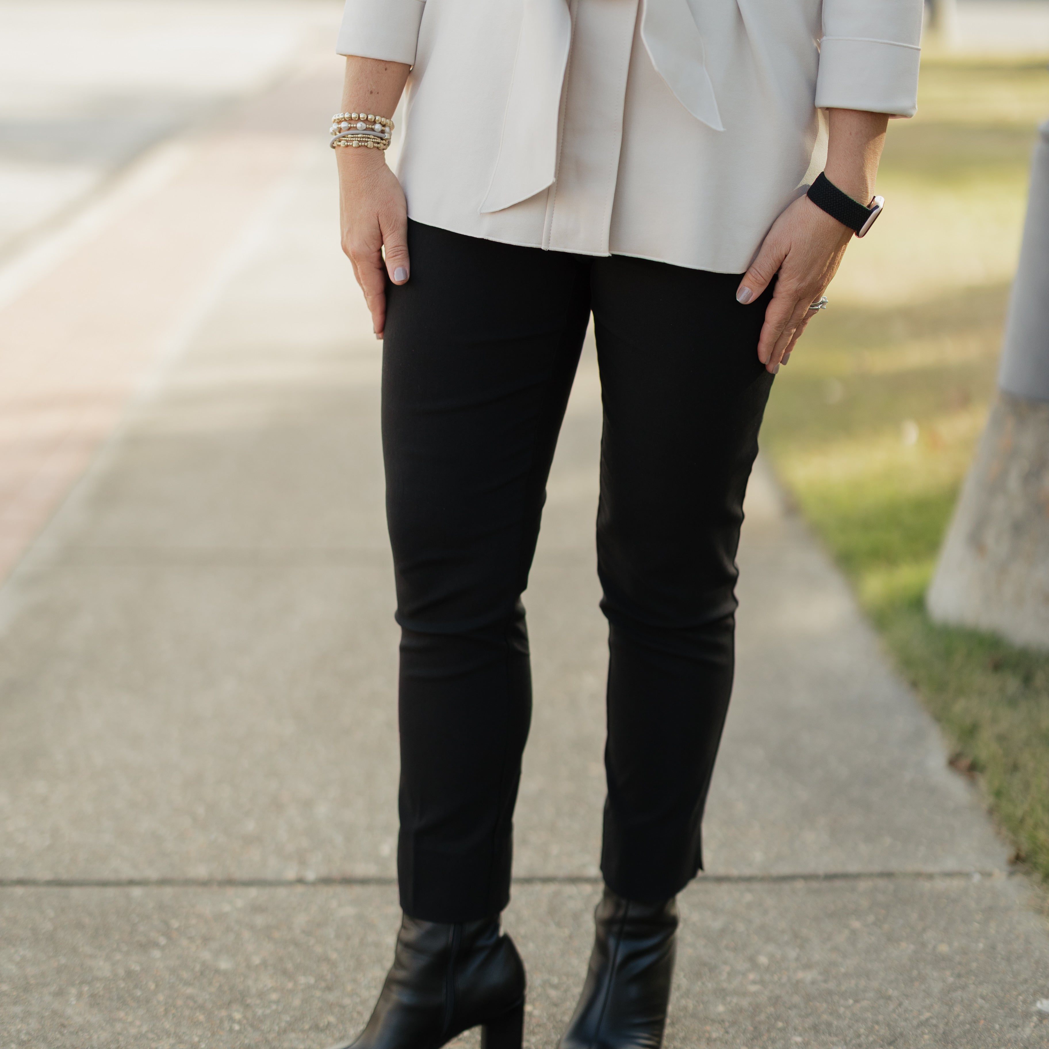 Person wearing a beige blazer, black pants, and black boots on a sidewalk.