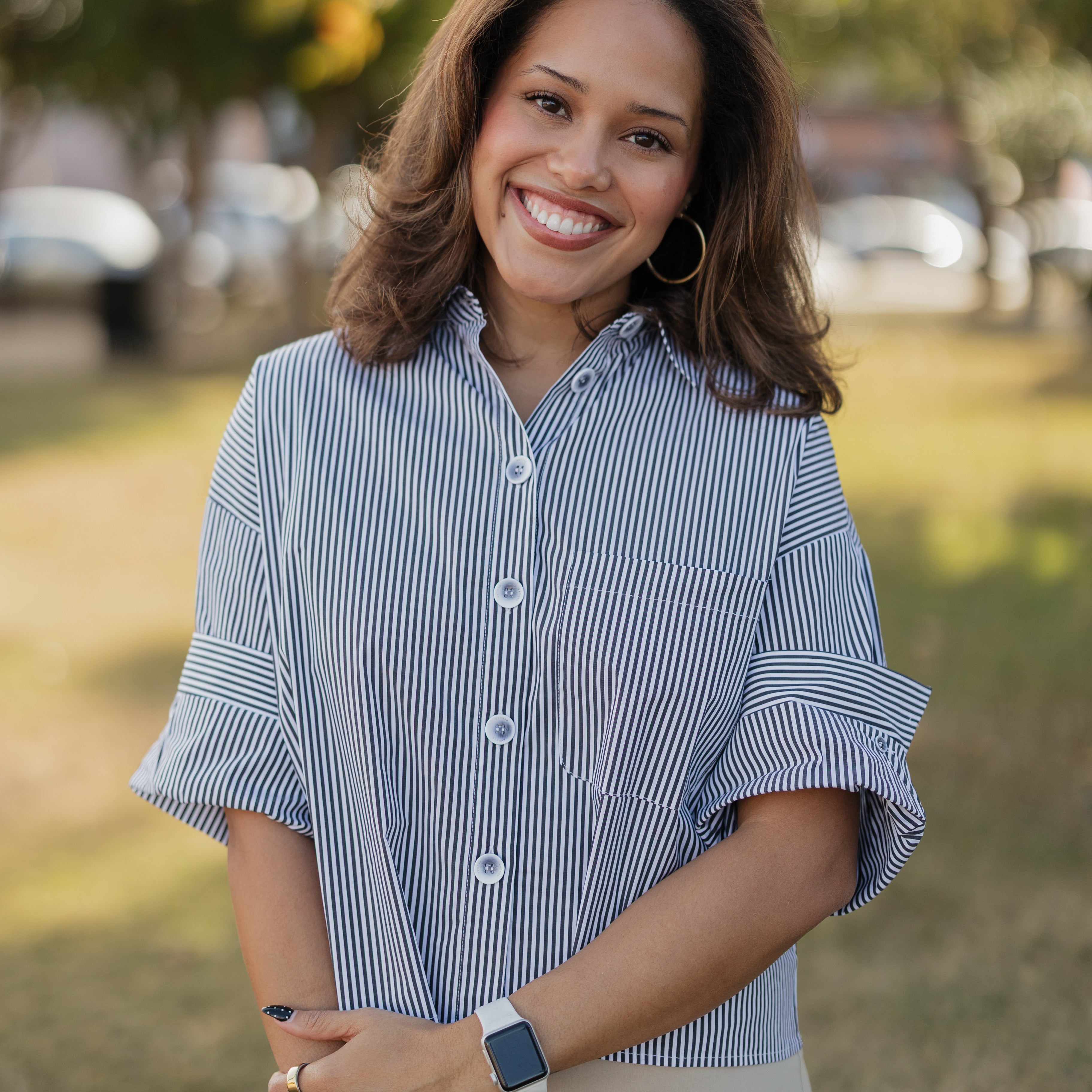 Woman wearing a black and white striped shirt outdoors with blurred background
