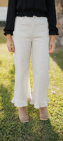 Person wearing sand colored pants with ruffled hem on a grassy background