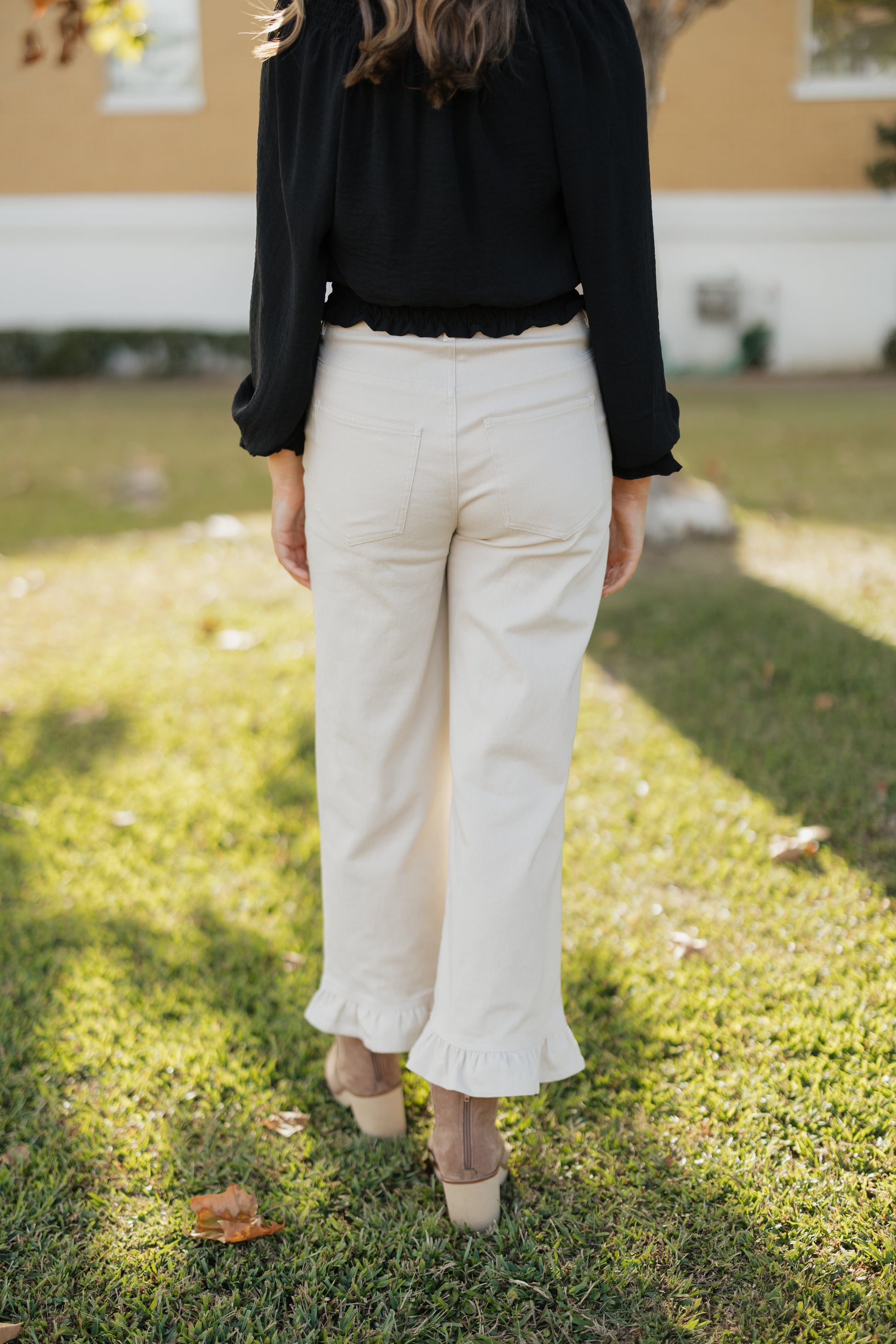 Person wearing a black top and sand colored pants standing on grass