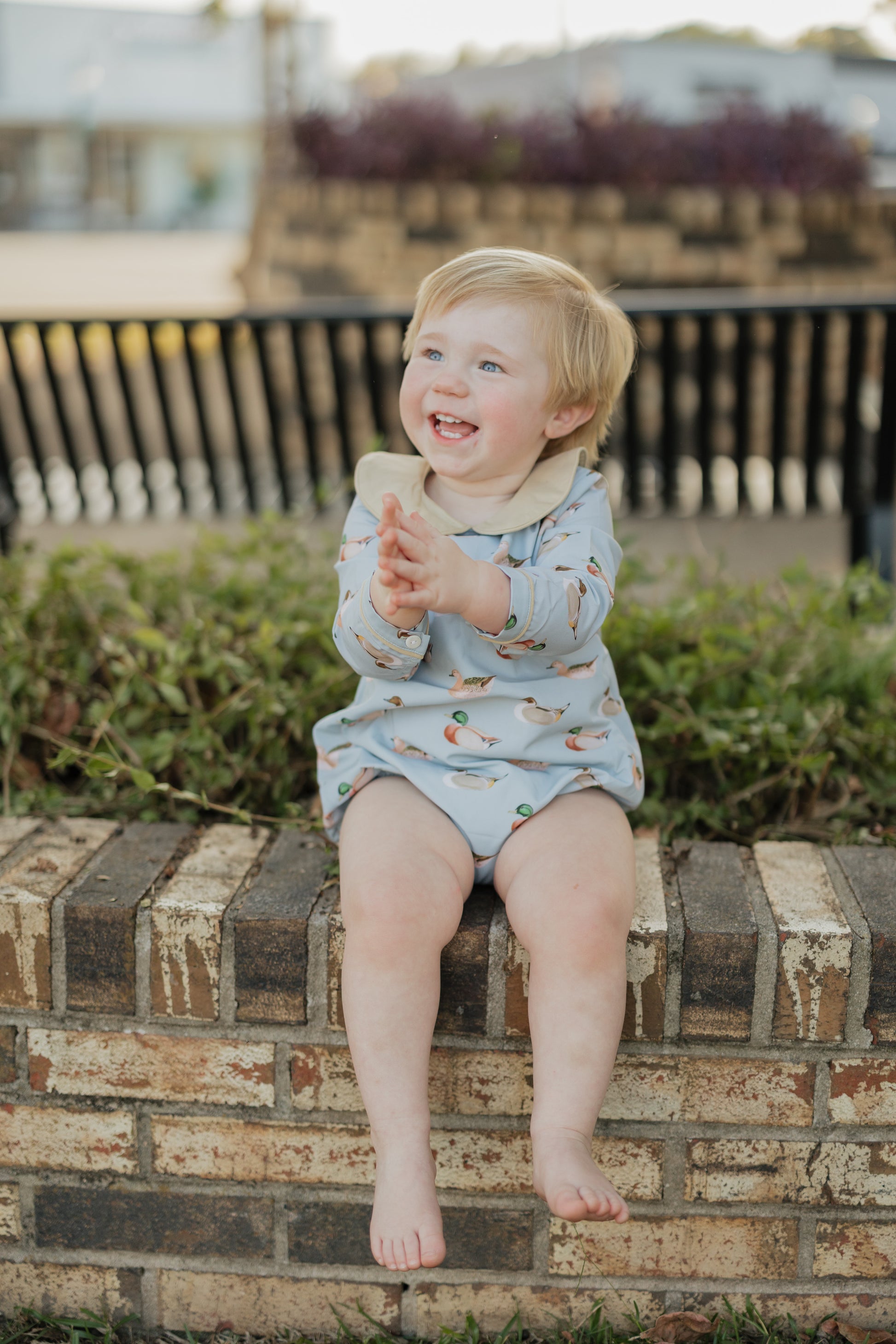 Child sitting on a brick wall outdoors holding a popsicle