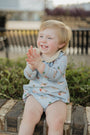 Child sitting on a wooden bench outdoors, clapping hands