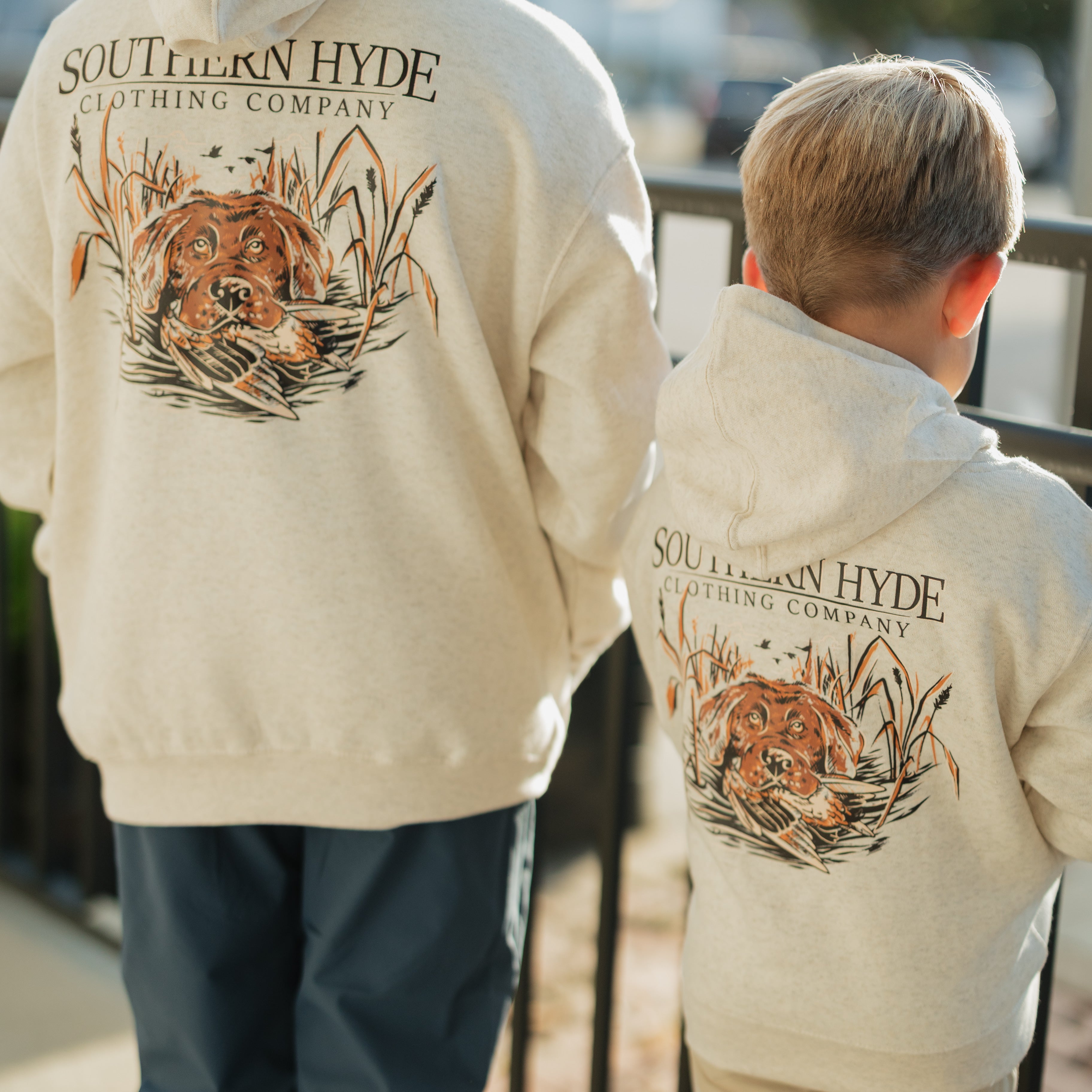 Two people wearing cream-colored hoodies with 'Southern Hyde Clothing Company' logo and tiger design.