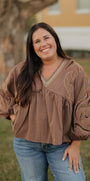 Woman wearing a brown blouse with intricate patterns outdoors