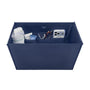 A navy blue fabric organizer box with multiple interior pockets, shown filled with various items including a white bottle, a tube, a pair of sunglasses, and a smartphone. The box is photographed on a clean white background.
