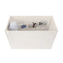 An off-white fabric organizer box with multiple interior compartments, shown holding various small items like a white bottle, a blue packet, eyeglasses, and a smartphone. The box is photographed on a seamless white background.