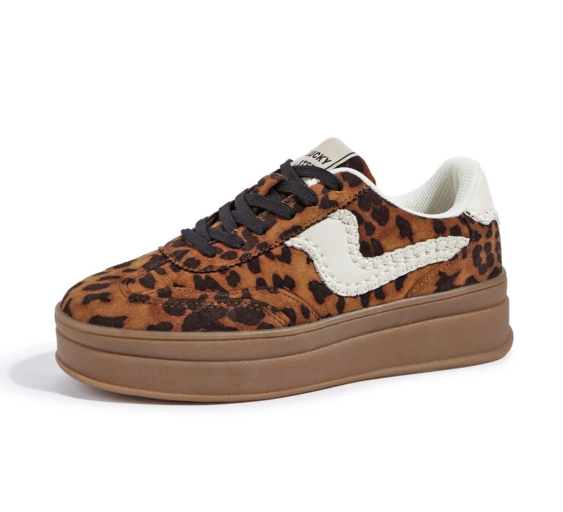 A platform sneaker featuring a brown and black leopard print upper, a thick brown gum sole, a white braided side accent, and a white heel tab.