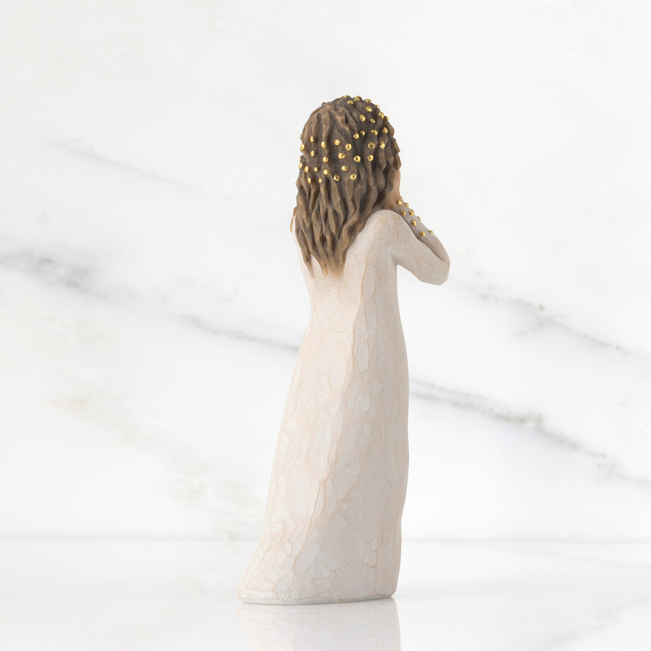Statue of a woman with braided hair and a white dress on a light background