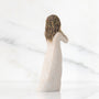 Statue of a woman with braided hair and a white dress on a light background