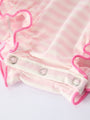 Close-up of a baby outfit with pink trim and buttons on a light background