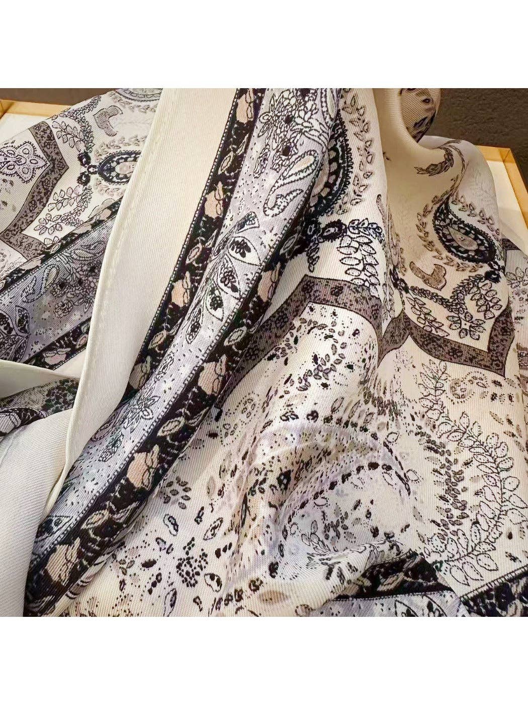 Muted grey vintage paisley triangle bandana scarf close-up, cream background with dark accents