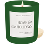 Green candle with a label reading 'Home for the Holidays' by Sweet Water Decor on a white background.
