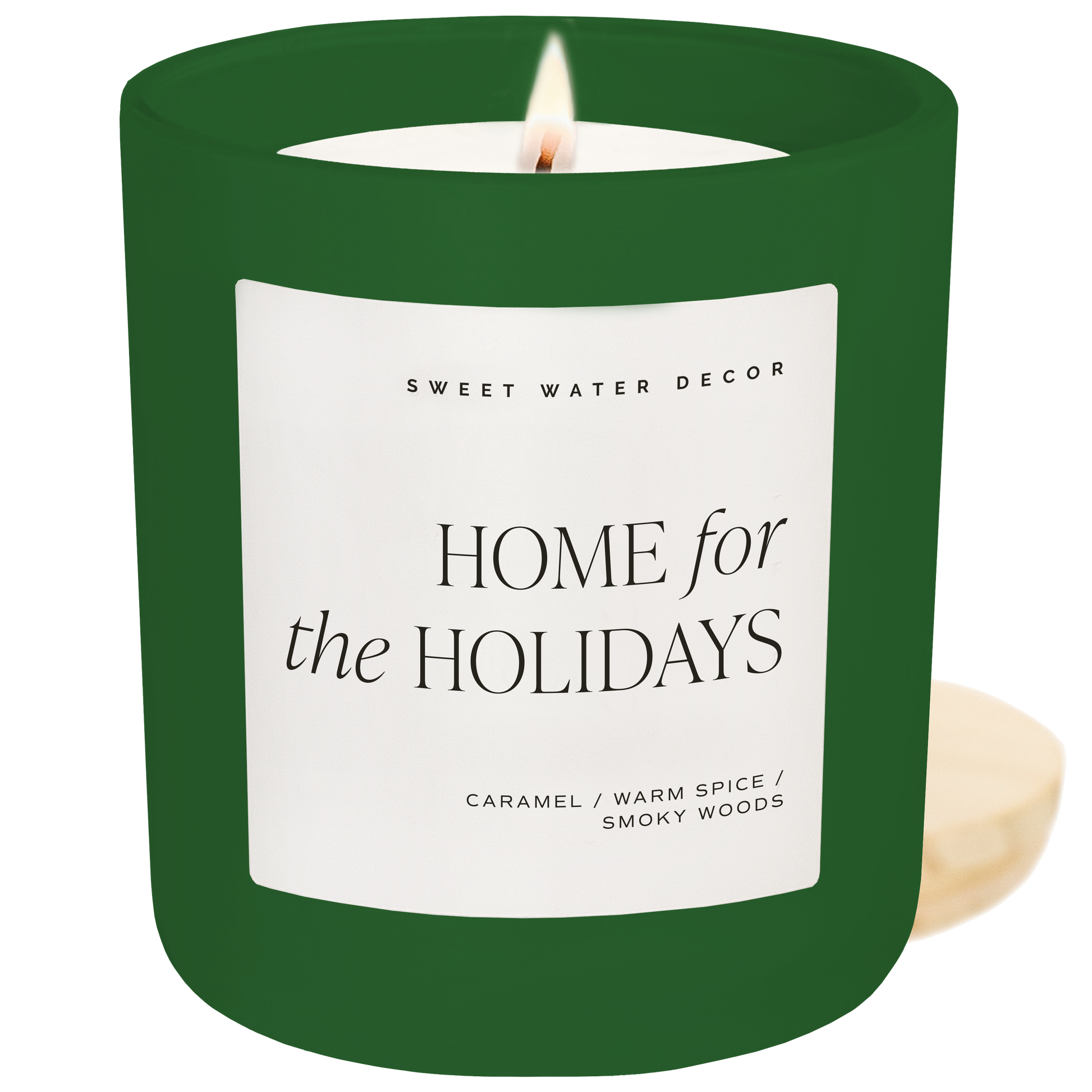 Green candle with a label reading 'Home for the Holidays' by Sweet Water Decor on a white background.
