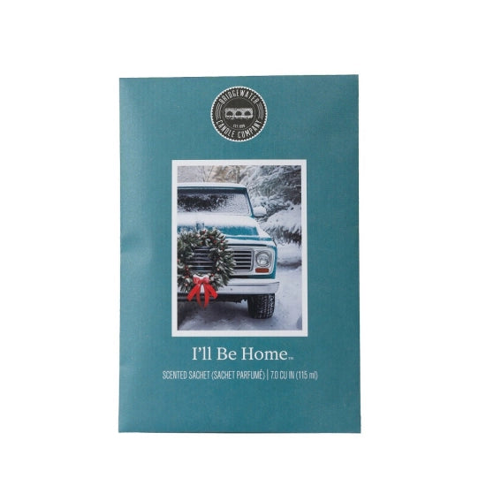 A teal scented candle packet from Candle Craft, featuring a vintage snow-covered truck with a wreath and red bow, and the text 'I'll Be Home.'.
