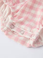 Pink and white checkered baby bloomers with a button on a light gray background