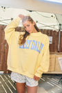 Person wearing a yellow sweatshirt with 'Dally Dally' text, standing outdoors.
