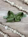 Green hair bow on a wooden surface with white beads