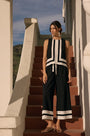 Woman in a black and white outfit standing on a set of stairs with a scenic background