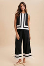 Woman wearing a black and white striped sleeveless top and wide-leg pants on a beige background