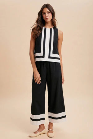 Woman wearing a black and white striped sleeveless top and wide-leg pants on a beige background