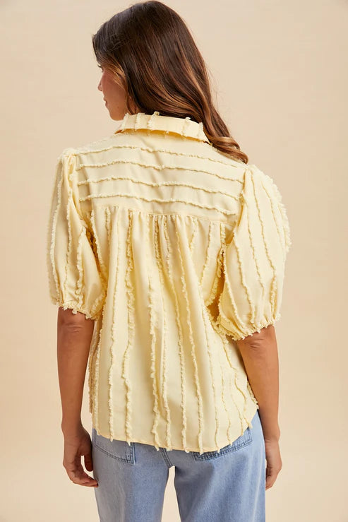 Woman wearing a yellow tie-dye blouse with blue jeans on a beige background