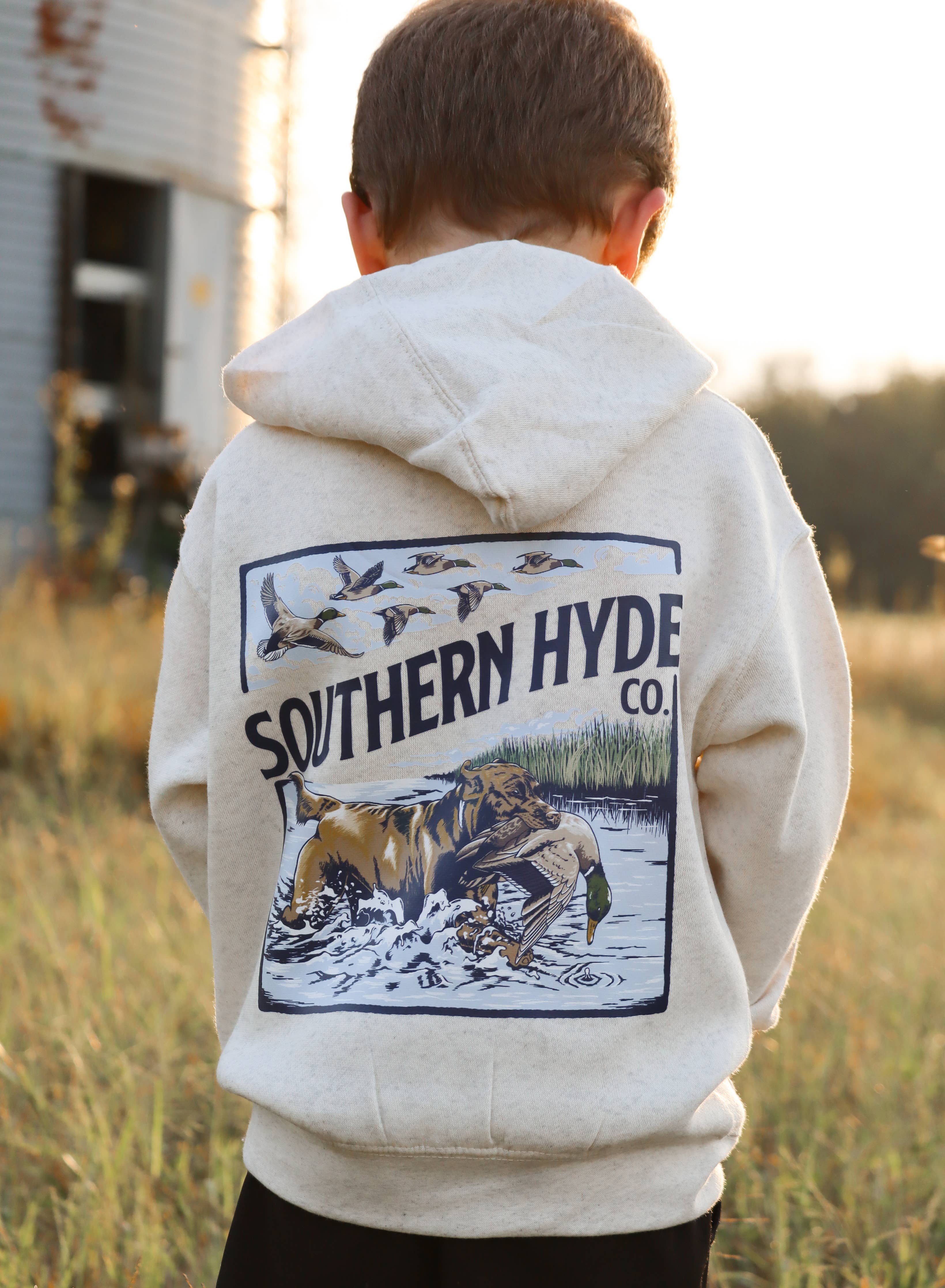 Child wearing a hoodie with 'Southern Hyde Co.' design in a field