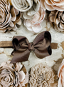 Brown hair bow on a textured surface with floral decorations