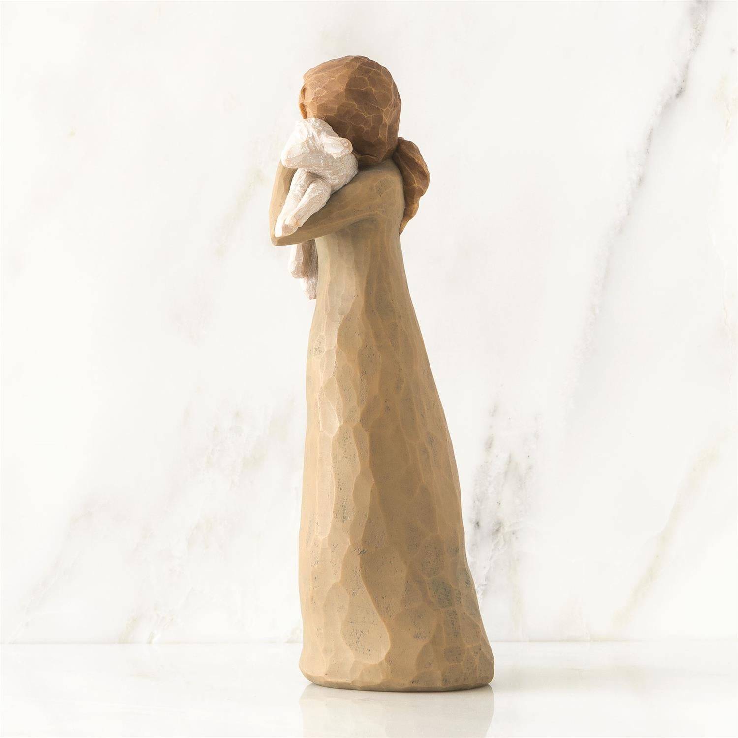 Wooden figurine of a woman holding a baby against a white background