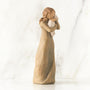 Wooden figurine of a woman embracing a child on a white background