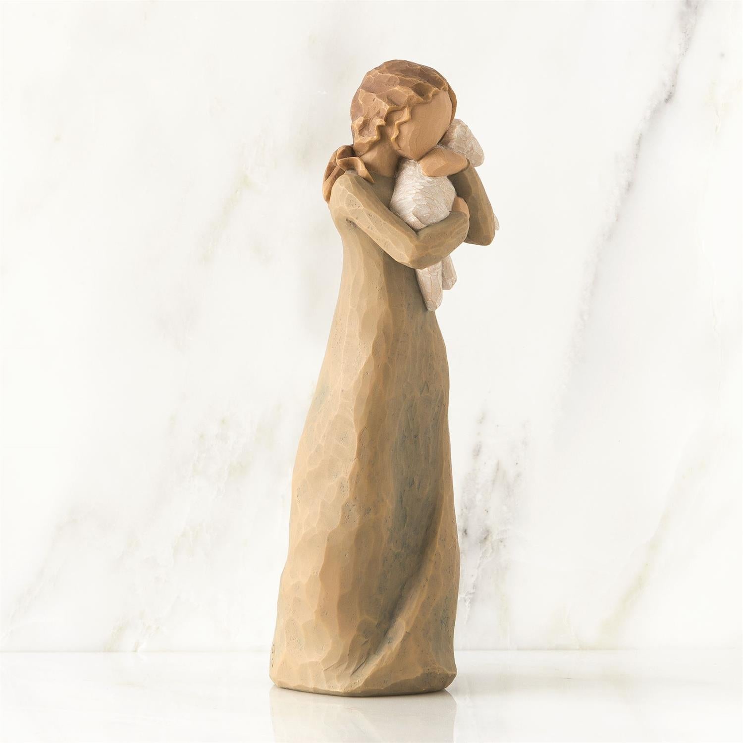Wooden figurine of a woman embracing a child on a white background