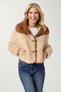 Woman wearing a beige sherpa jacket with brown collar and buttons on a white background