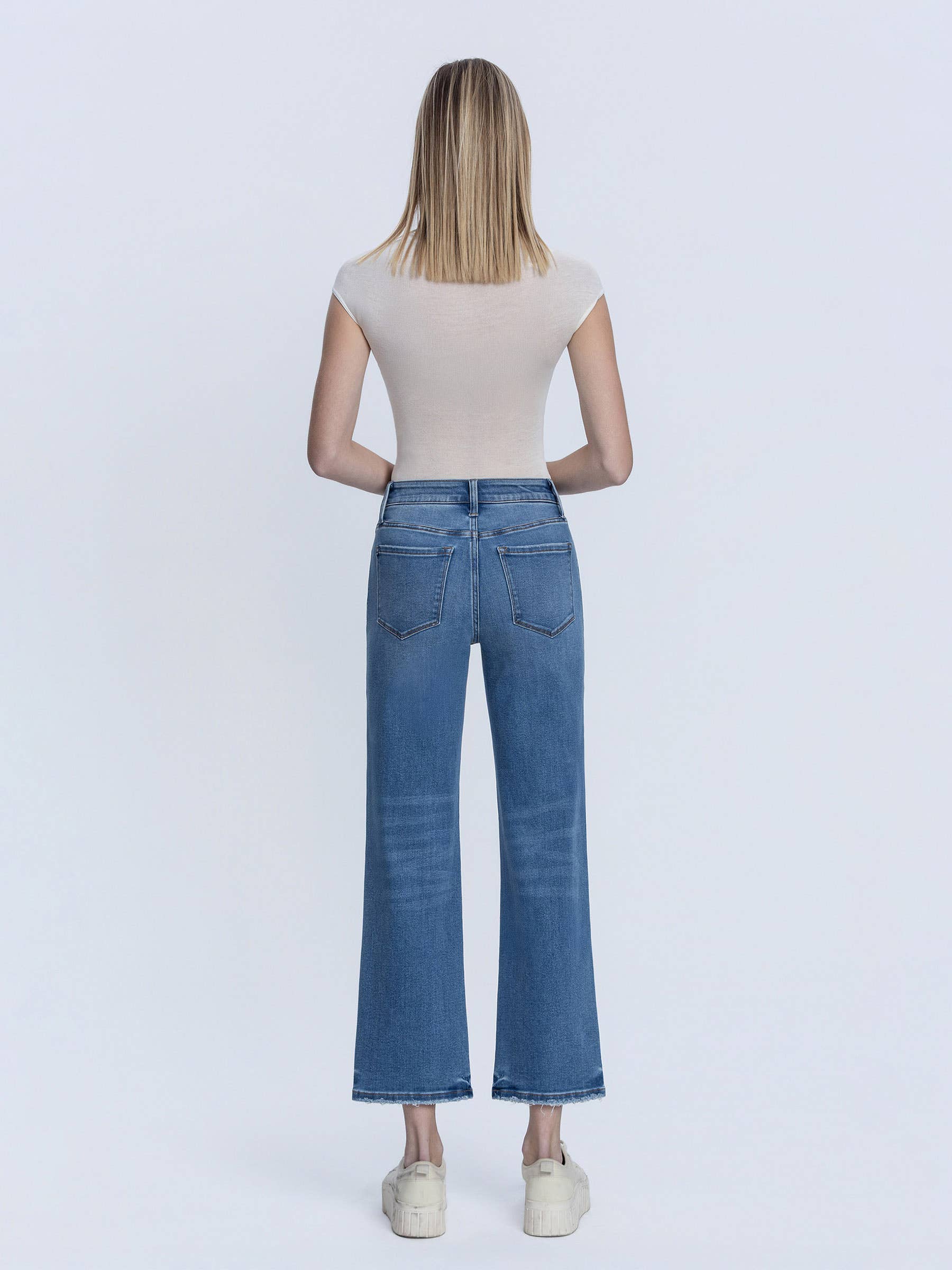 Person wearing blue jeans and a white top on a white background