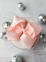 Pink bow on a small round object with decorative silver balls in the background