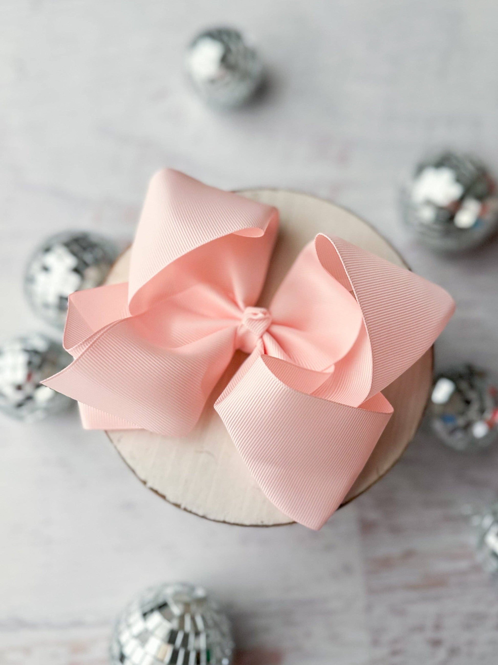 Pink bow on a small round object with decorative silver balls in the background
